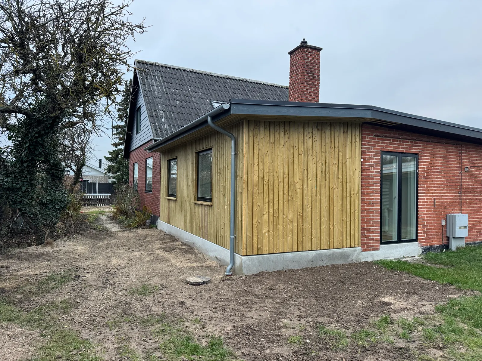 Vårfluevej Rødovre — ny 18 m² tilbygning med lys vertikal træbeklædning op mod den eksisterende røde murstensgavl
